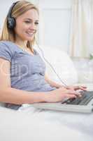 Woman listening music through headphones while using laptop