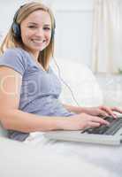 Woman listening music through headphones while using laptop