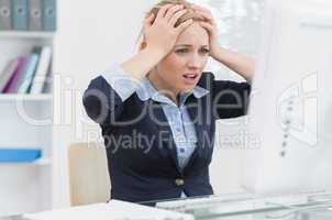 Frustrated business woman in front of computer at office desk