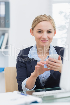 Portrait of business woman text messaging at office desk