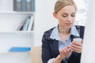 Young business woman text messaging at office desk