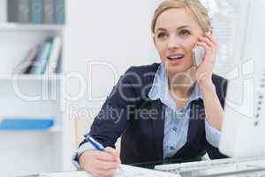 Business woman writing while on call at office