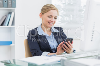 Young business woman text messaging office desk