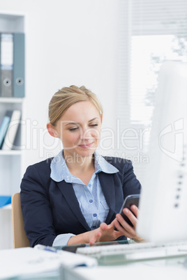 Young business woman text messaging at office desk