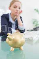 Upset business woman with piggy bank at office