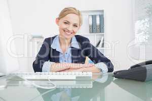 Smiling confident business woman with computer at desk
