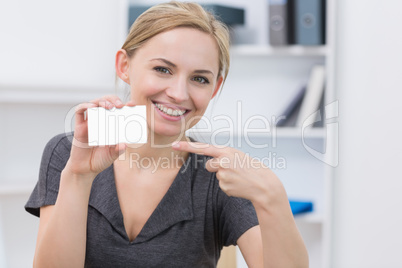 Female executive pointing at blank card at office