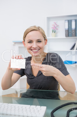 Female executive pointing at blank card at office