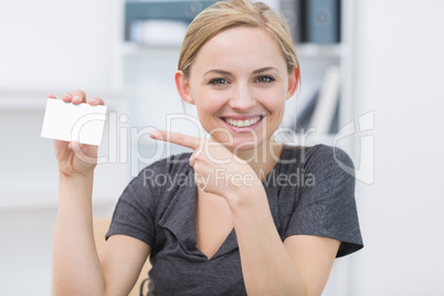 Female executive pointing at blank card at office