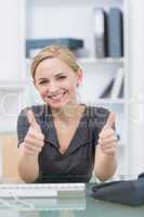 Female executive gesturing double thumbs up at office