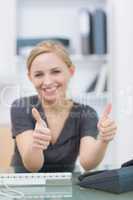 Female executive gesturing double thumbs up at office