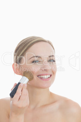 Portrait of smiling young woman putting on make-up