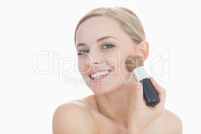 Portrait of smiling young woman putting on make-up