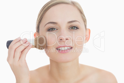 Close-up portrait of young woman putting on make-up