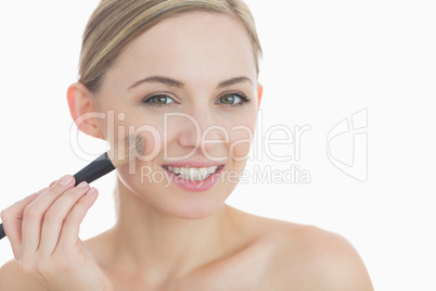 Portrait of smiling young woman putting on make-up