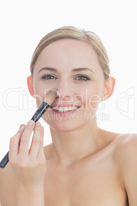 Portrait of smiling young woman putting on make-up