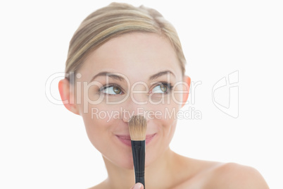 Close-up of smiling young woman with make-up brush
