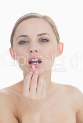 Close-up portrait of young woman applying lipgloss