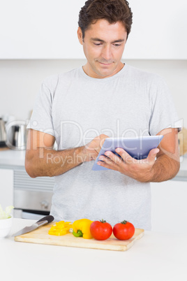 Man consulting tablet while chopping vegetables