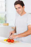 Smiling man slicing peppers