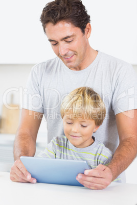 Son and father using tablet together