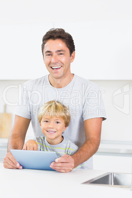 Laughing father and son using tablet