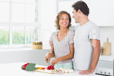 Husband embracing wife as she prepares vegetables