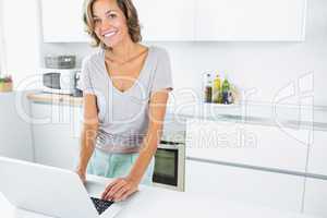 Pretty woman in kitchen with laptop
