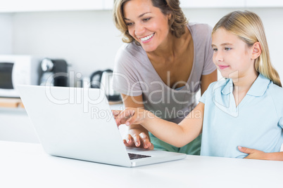 Happy mother and daughter using laptop