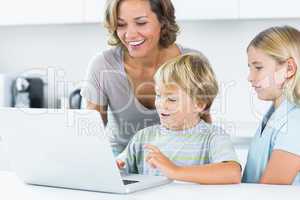 Mother using laptop with her children