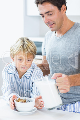 Father pouring milk onto sons cereal