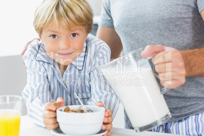 Father pouring milk for sons cereal