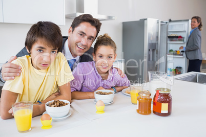 Smiling father and children having breakfast