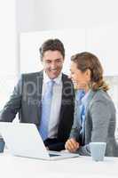 Smiling couple using laptop before work