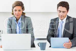Couple using media devices in kitchen