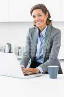 Woman typing on laptop in the kitchen before work