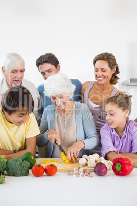 Family watching grandmother slicing pepper