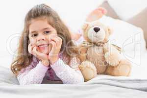 Girl lying on bed with teddy bear
