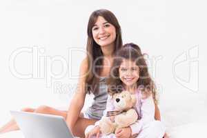 Smiling mother and daughter using laptop