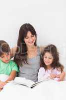 Mother and children reading book together