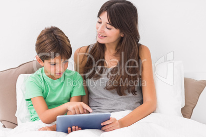 Smiling mother using digital tablet with son