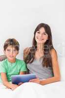 Smiling son and mother using tablet