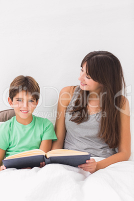 Smiling mother and son reading in bed