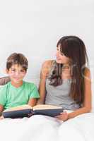 Smiling mother and son reading in bed