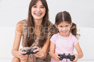 Happy mother and daughter playing video games