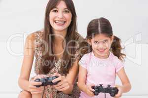 Happy mother and daughter playing video games