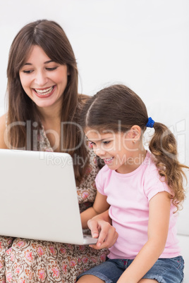 Happy mother and daughter using laptop