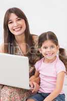 Mother and daughter happily using laptop