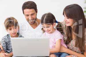 Smiling family using laptop on couch