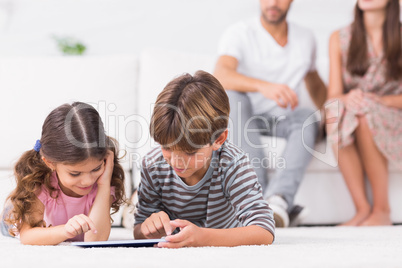 Brother and sister using tablet pc together on floor
